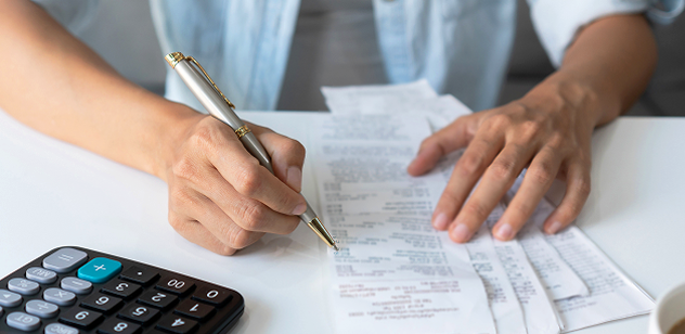 Person calculating property tax bill with a calculator and receipts